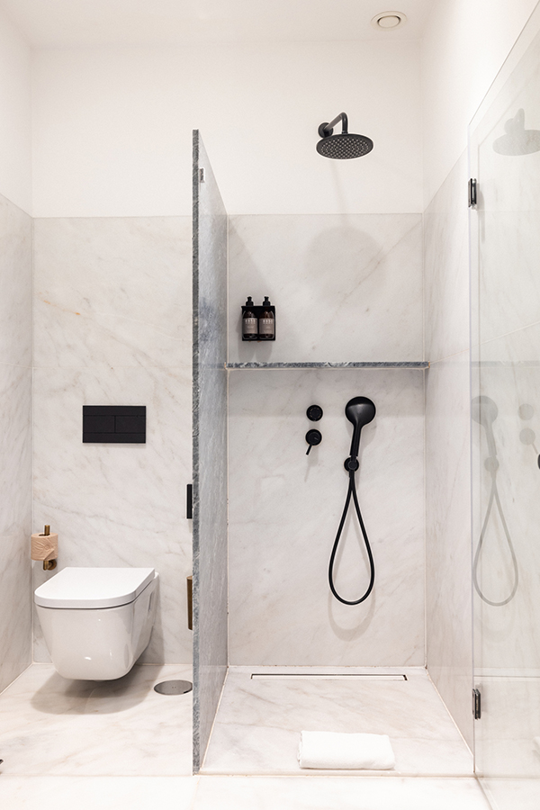 Marble bathroom at the Lisbon boutique hotel with rain shower and matte black fixtures.